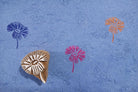 Hand carved wooden daisy bloom block printing stamp creating colorful floral prints on handmade blue paper.