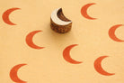 Hand carved wooden crescent moon block stamp making orange prints on handmade paper