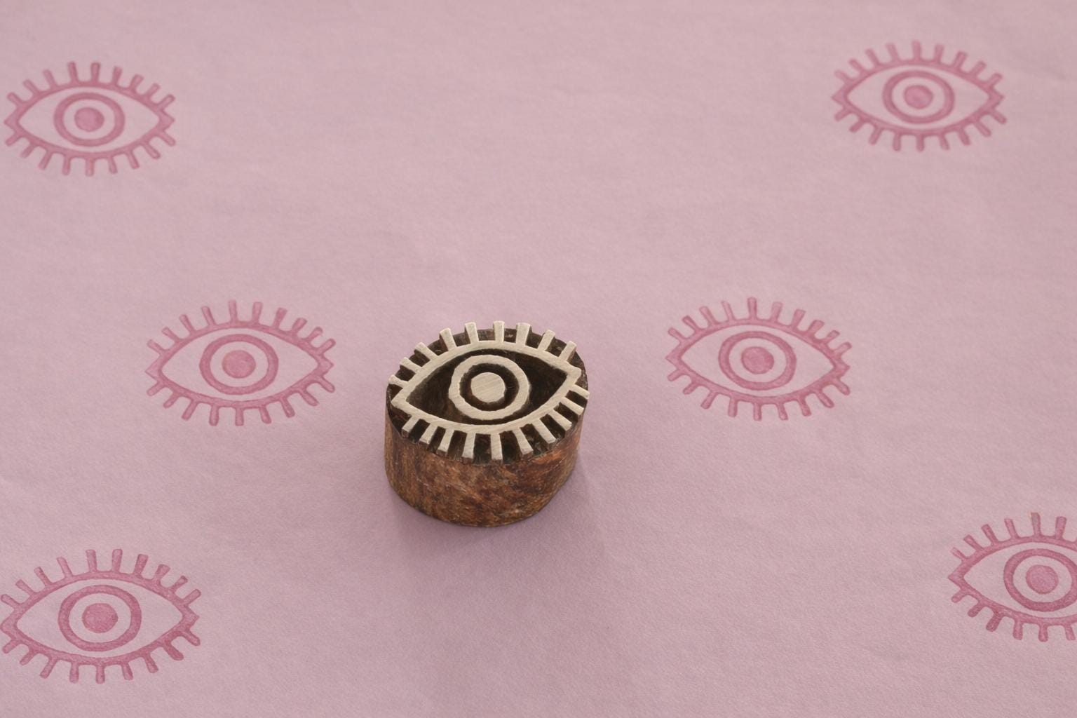 Carved wooden evil eye block stamp printing pink eye pattern on handmade paper