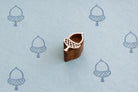 Hand carved wooden acorn printing block stamp shown with blue acorn prints on faded blue background.