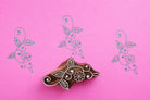 Hand carved wooden vine floral block printing stamp creating green vine prints on pink paper.