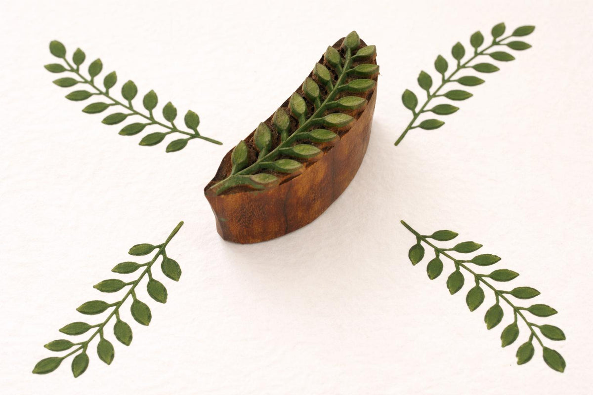 Hand carved wooden leaf textile stamp with green repeating botanical print on fabric