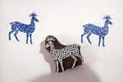 Hand carved wooden deer block stamp creating blue deer prints with dotted pattern on white paper.