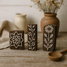 Set of three hand carved Indian wooden block printing stamps with floral and botanical designs on rustic wooden surface.