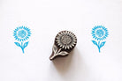 Hand carved sunflower wooden block printing stamp creating blue sunflower prints on white paper.