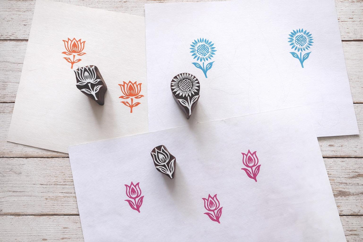 Hand carved wooden floral block printing stamps showing lotus tulip and sunflower prints on handmade paper.