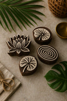 Set of four hand carved wooden block printing stamps including lotus flower, lily pad, and concentric circle designs styled with tropical leaves.
