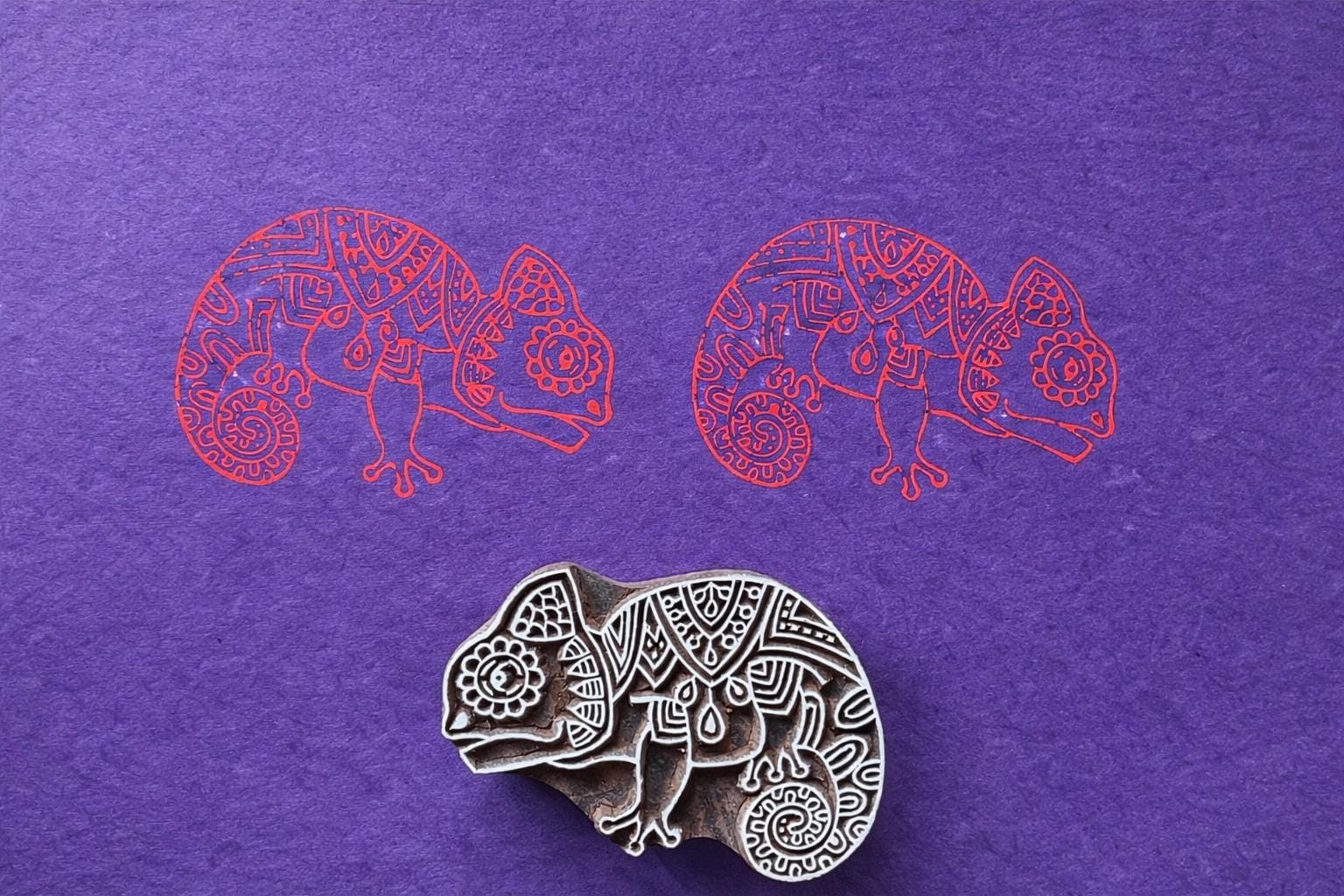Chameleon block printing stamp with printed animal pattern on purple paper.