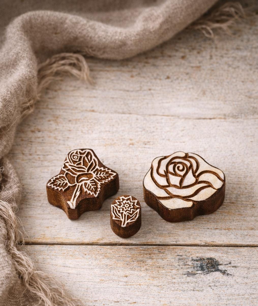Set of hand carved Indian wooden rose printing stamps in different sizes on off white background.