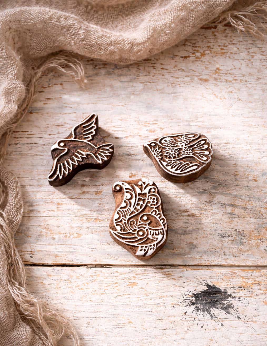 Set of three hand carved Indian bird wood printing blocks arranged on a white background.