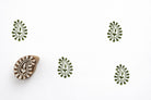 Hand carved decorative paisley wood block stamp creating green repeat prints on white paper.