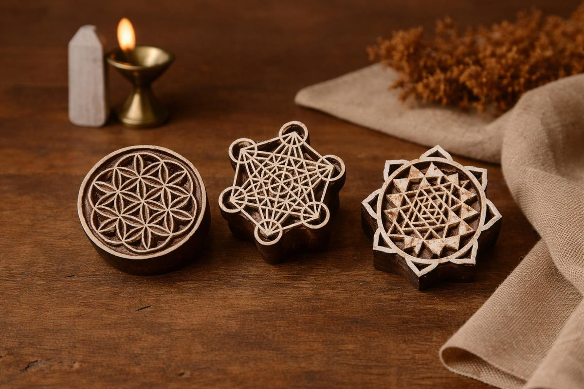 Hand carved wooden sacred geometry block printing stamps featuring flower of life, metatron cube, and sri yantra designs on a wooden table.