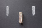 Hand carved leaf textile stamp made from wood showing white leaf prints on dark paper.