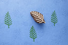 Leaf fabric stamp creating repeating green leaf prints using a hand carved wooden printing stamp.