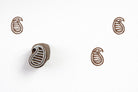 Hand carved wooden striped paisley block printing stamp creating brown paisley prints on white paper.
