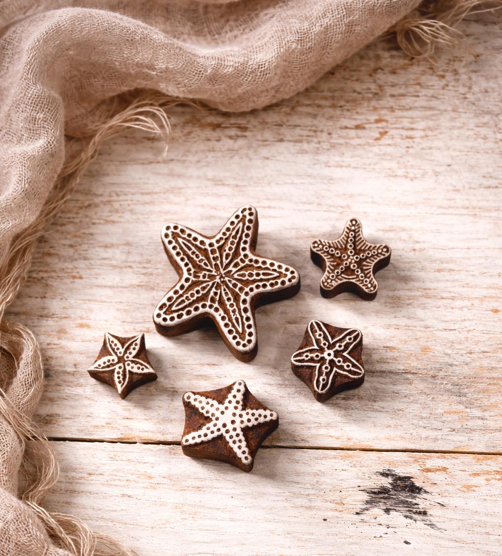 Set of five hand carved Indian wooden block printing stamps with starfish designs displayed together on a white surface.