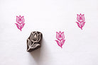 Hand carved tulip flower wooden block printing stamp creating pink tulip prints on white paper.
