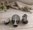 Hand carved wooden block printing stamps featuring tree, bird and leaf designs arranged on a rustic wooden table.