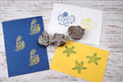 Wooden octopus, starfish, and mermaid block printing stamps displayed with colorful printed samples on paper.