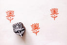 Hand carved lotus flower wooden block printing stamp creating orange lotus prints on textured white paper.