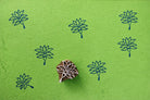 Wooden lotus flower block printing stamp creating dark blue lotus prints on bright green paper.
