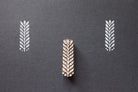 Hand carved leaf textile stamp made from wood showing white leaf prints on dark paper.