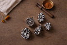 Five hand carved wooden block printing stamps with floral and paisley motifs placed on rustic wooden table with cloth and natural dye bowl.