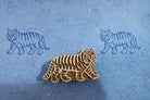 Hand carved wooden walking tiger block printing stamp creating blue tiger prints on textured handmade paper.