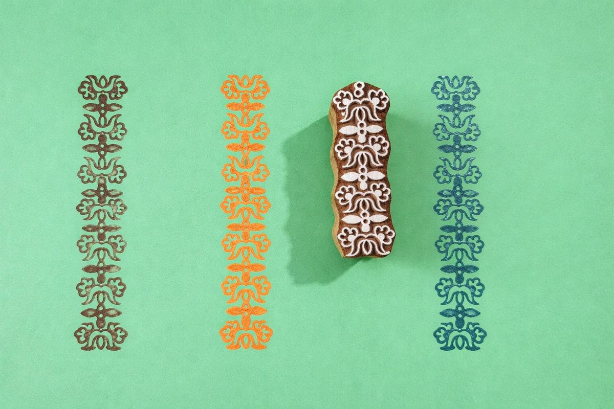 Hand carved wooden heritage motif border block printing stamp creating repeating vertical pattern on green background.
