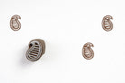 Hand carved wooden striped paisley block printing stamp creating brown paisley prints on white paper.