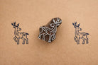 Hand carved wooden deer block printing stamp creating navy blue deer prints on brown kraft paper background.