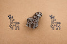 Hand carved wooden deer block printing stamp creating navy blue deer prints on kraft paper.