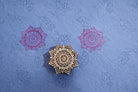 Hand carved wooden mandala flower block printing stamp creating pink mandala prints on blue handmade paper.