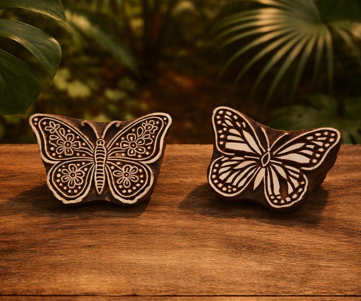 Hand carved wooden butterfly block printing stamps on wooden table, featuring floral garden butterfly and wild meadow butterfly designs, natural brown wood blocks with cream carved surface
