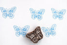Blue butterfly block print pattern on white handmade paper using wild meadow butterfly wooden stamp, repeated print design showing clean crisp impressions