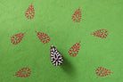 Jaipuri motif wooden printing block producing red prints on green paper.