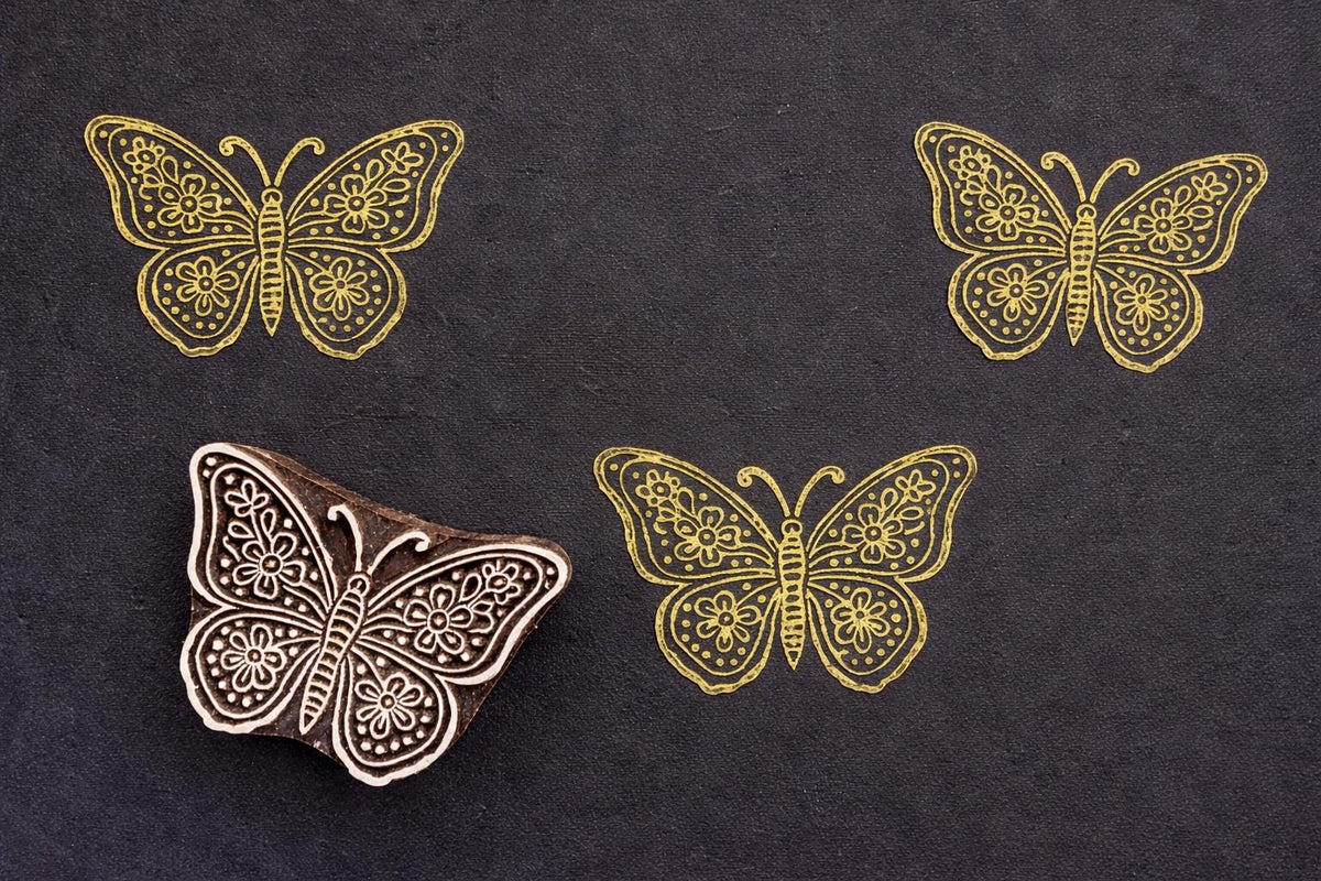 Gold floral butterfly block print on dark textured paper with hand carved wooden stamp, detailed floral garden butterfly design with decorative wings