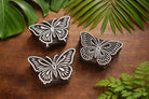 Set of three hand-carved wooden butterfly block stamps with intricate wing patterns on rustic background