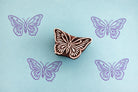 Folk art butterfly wood stamp with blue butterfly prints on blue background