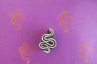 Wooden snake block stamp with flowing serpent design and orange prints on purple background