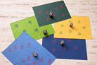 Five wooden botanical block printing stamps showing repeating patterns printed on blue, green, and yellow paper backgrounds.