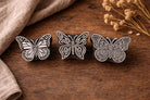 three hand carved wooden butterfly stamps on rustic wooden surface