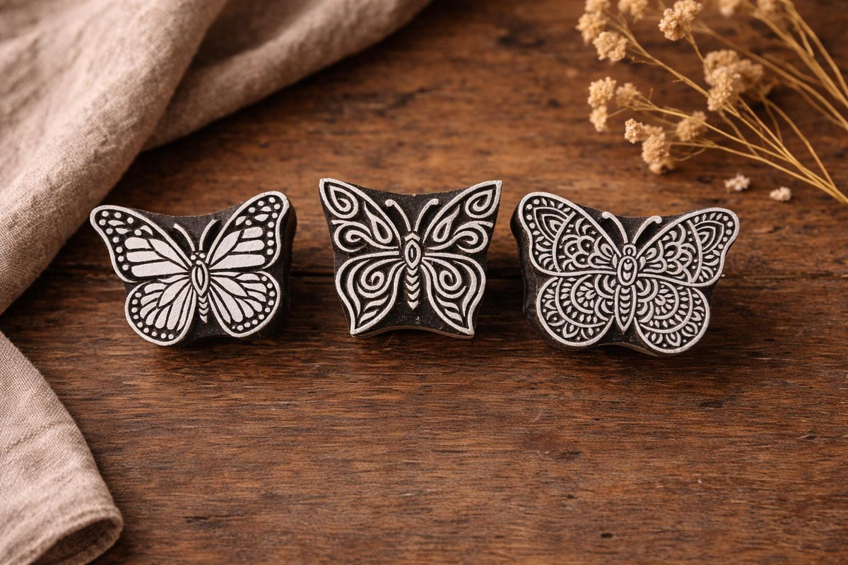 three hand carved wooden butterfly stamps on rustic wooden surface