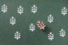 Floral branch wooden printing block producing white prints on dark green paper.
