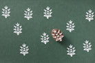 Floral branch wooden printing block producing white prints on dark green paper.