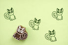 Hand carved wooden kitten block printing stamp creating green cat prints on green paper.
