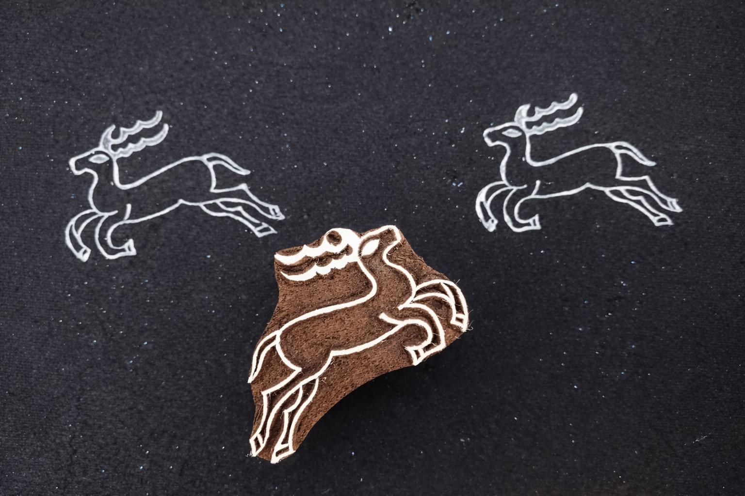 hand carved wooden running deer stamp with white ink prints on black background