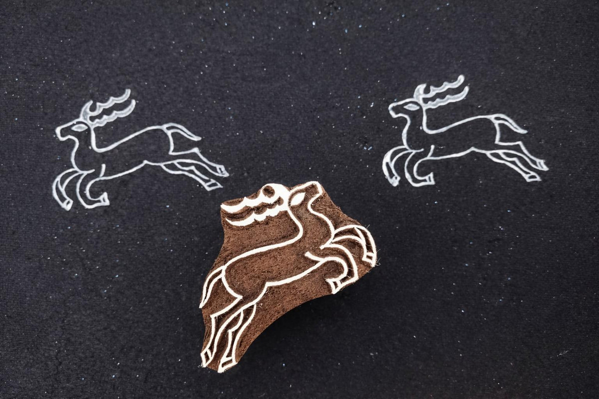 hand carved wooden running deer stamp with white ink prints on black background
