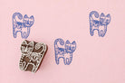 Hand-carved wooden cat stamp with whimsical folk art design, shown on a soft pink background with blue printed cat patterns.