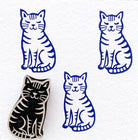 Sleepy striped cat wooden block printing stamp creating deep blue cat prints on white fabric background.